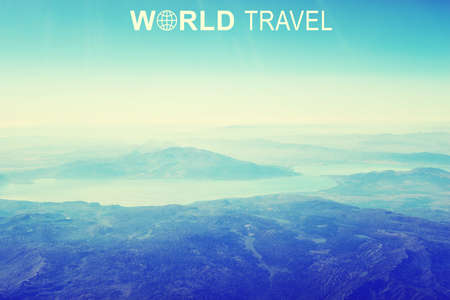Aerial view of mountainous desert terrain, sky and clouds. Inscription World Travel and related symbolの写真素材