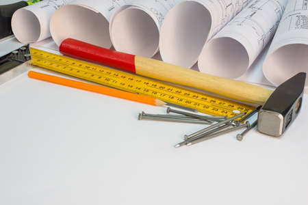 Drawing rolls, hammer, nails, builder\'s level, pencil, tri-square on white surfaceの写真素材