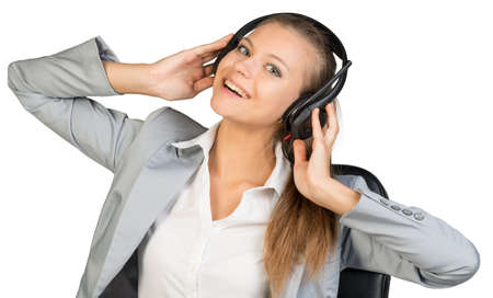 Businesswoman in headset with her hands on speakers, her had tilted back and sideways, looking at camera, laughing. Isolated over white backgroundの写真素材