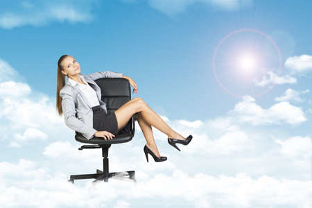 Woman sitting in chair feet up on handle. Background of clouds, sky and sunの写真素材