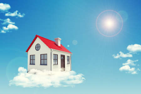 White house with red roof, brown door and chimney in cloud. Background sun shines brightly. Blue skyの写真素材