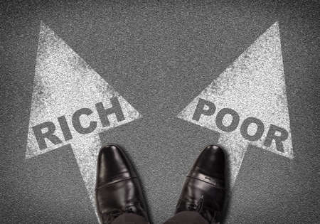 Top view of shoes standing on asphalt with two arrows. Words rich and poor. Business conceptの写真素材