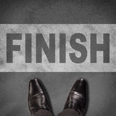 Top view of shoes standing on asphalt road with line and word finish. Business conceptの写真素材