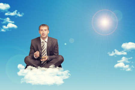 Businessman sitting in lotus position on cloud, holding golden lamp of Aladdin. Sky with sun as...