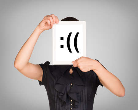 Woman in black dress covered her face with tablet. On screen code smiley. Gray background