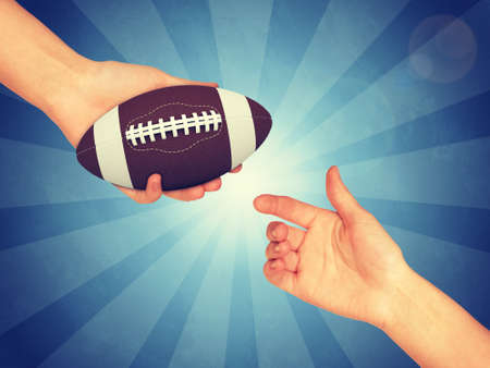 Synthetic rugby ball in hand. Abstract blue backround. Light with stripesの写真素材