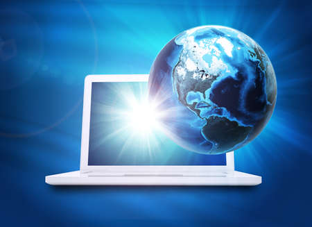 Earth model above laptop on abstract blue background. 