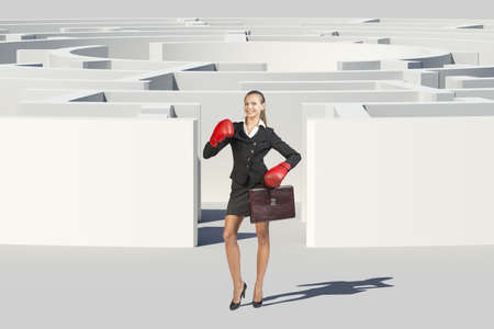 Businesswoman in boxer gloves shouting and looking at camera, near labyrinth, closed view. Isolated...