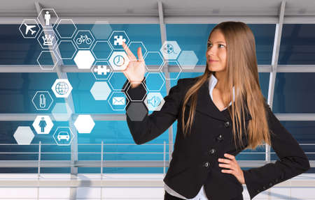 Buinesswoman in suit pressing on holographic screen with iconsの写真素材