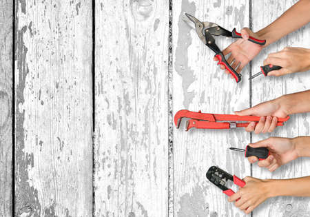 Set of peoples hands holding different tools on old white board texture backgroundの写真素材