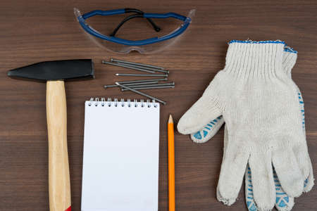 Welding goggles with set of scattering nails and note pad on brown wood table, top viewの写真素材