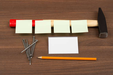 Stickers on hammer with set of scattering nails on brown wood tableの写真素材