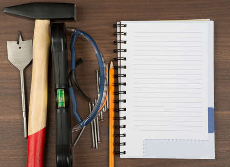 Different working tools with note pad and pencil on brown wood table, close-up viewの写真素材
