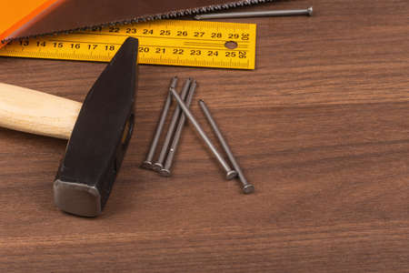 Hammer with ruler and documents on brown wood table, close-up viewの写真素材