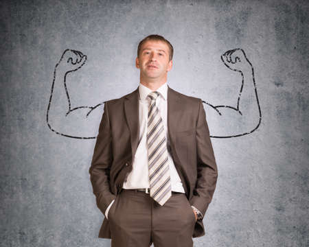 Businessman with strong arms drawn in pencil on wall texture background, looking at cameraの写真素材