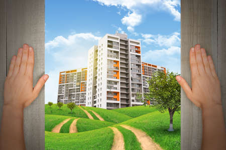 Humans hands and city under cloudy blue sky with road and treesの写真素材