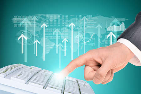 Businessmans finger touching keyboard on abstract blue background with world map and arrowsの写真素材