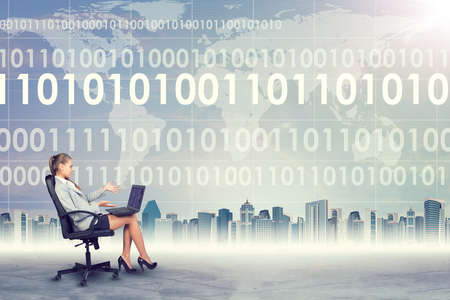 Surprised woman sitting in chair working on laptop on abstract virtual background with world mapの写真素材