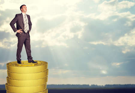 Businessman standing on coins stack and looking upの写真素材