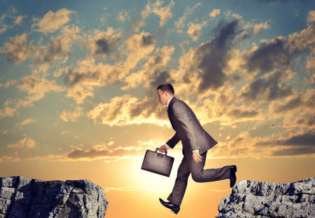Businessman with suitcase falling into abyss on nature backgroundの写真素材
