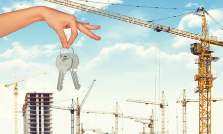 Hand holding keys on construction site background, Industrial backgroundの写真素材