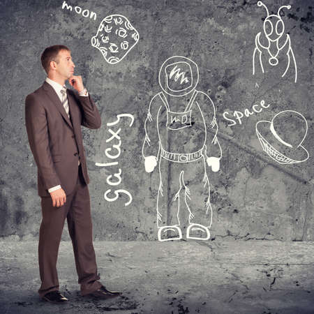 Thinking businessman in profile on abstract background with drawn picturesの写真素材