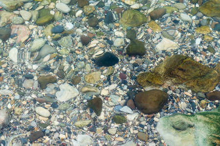 Stones under clear water with wave, close up viewの写真素材