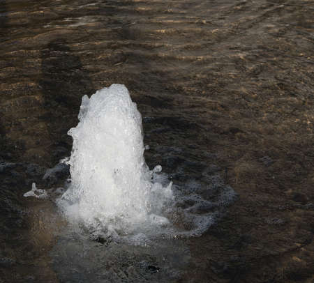 Small geyser in clear transparent sea with waves