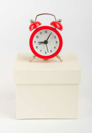 Red alarm clock on white box on isolated white backgroundの写真素材