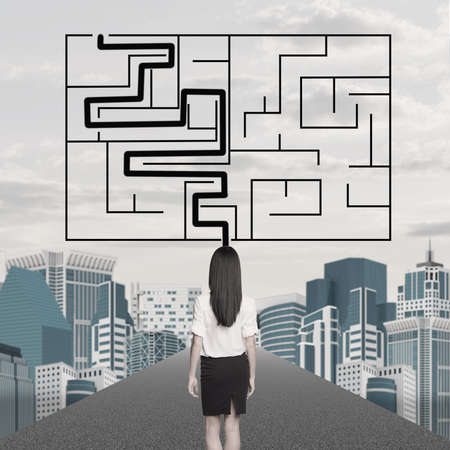 Businesslady with labyrinth and cityscape background, back viewの写真素材