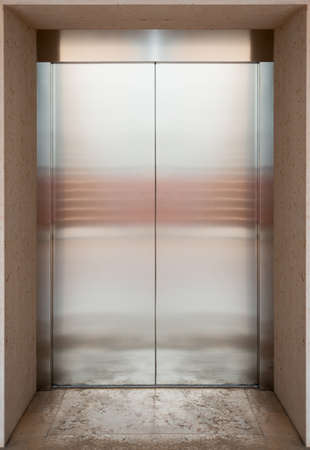Metal lift in building with reflection and marble floor