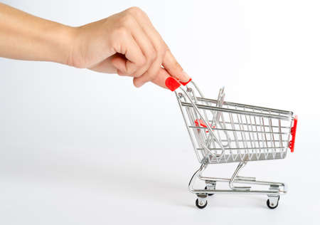 Shopping cart with humans hand on isolated white background, side viewの写真素材