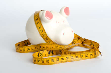 Piggy bank with tape measure on isolated white background, side viewの写真素材
