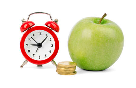 Fresh apple with coins and alarm clock on isolated white backgroundの写真素材