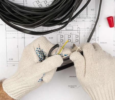 Mans hands cutting cable on draft backgroundの写真素材