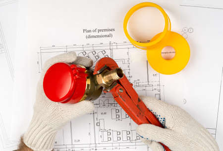 Mans hands in gloves holding water meter on draft background