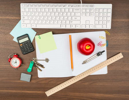 Apple with office supplies on wooden table