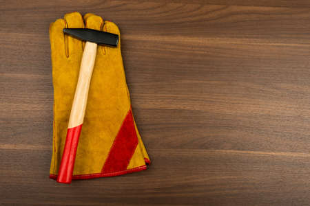 Hammer on construction gloves on wooden tableの写真素材