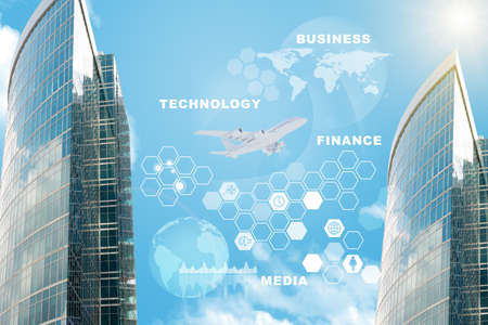 Skyscrapers with world map and computer icons on blue sky backgroundの写真素材