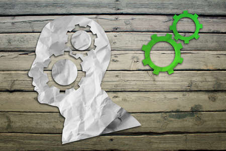 Paper humans head with wheel symbols on wood deck backgroundの写真素材