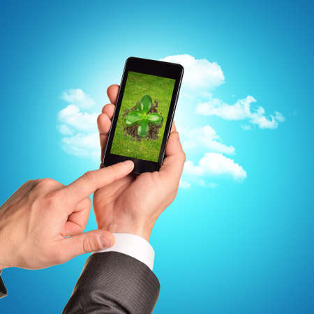 Businessman holding phone with plant on blue backgroundの写真素材