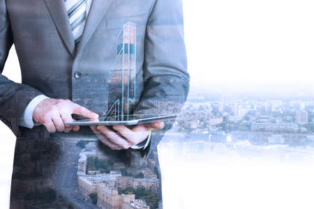 Businessman holding tablet with 3d city model on cityscape backgroundの写真素材