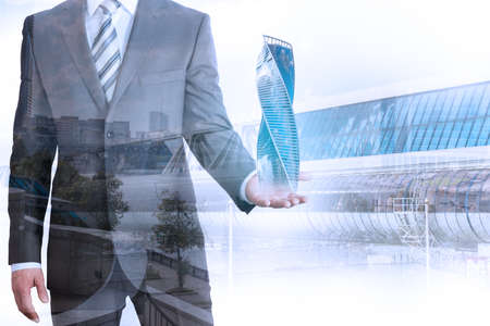 Businessman holding 3d city model on cityscape background