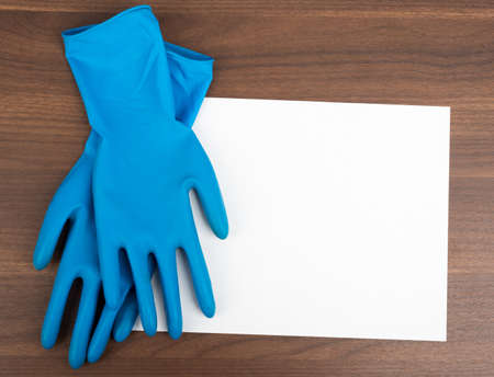 Blank paper with rubber gloves on wooden table