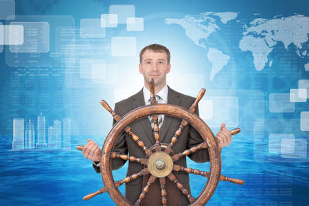 Businessman holding steering wheel on abstract background with world mapの写真素材