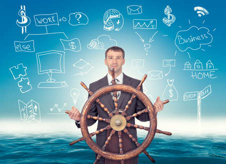 Businessman holding steering wheel on abstract background with symbolsの写真素材