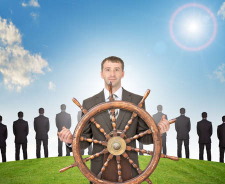 Businessman holding steering wheel on nature background with green grassの写真素材