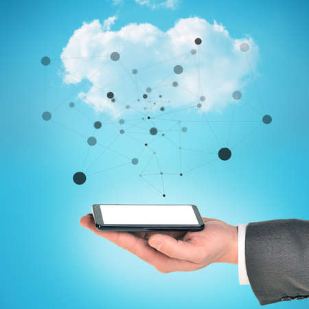 Businessman arm holding smartphone on blue sky background