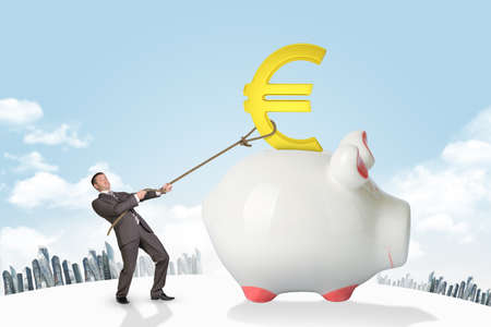 Businessman holding euro sign with rope on piggy bank on city backgroundの写真素材