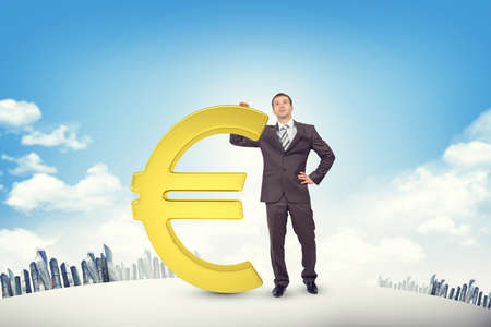 Businessman leaning on euro sign on cityscape backgroundの写真素材